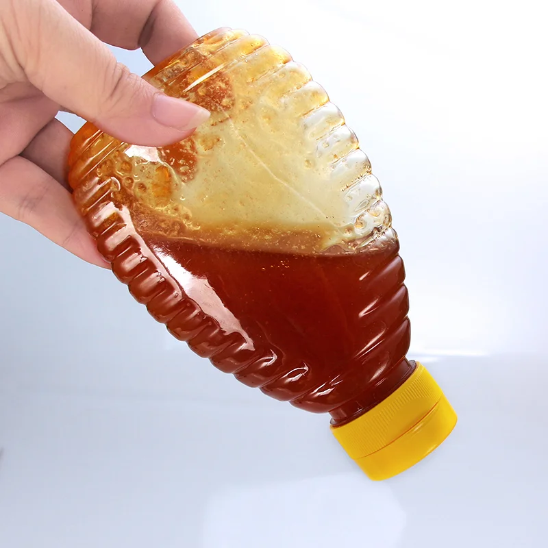 A ribbed honey squeeze bottle being dispensed through its flip-top cap